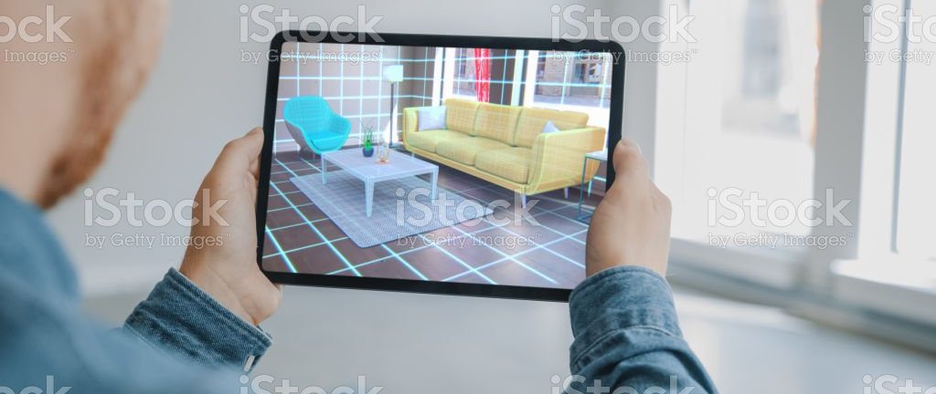 Decorating Apartment: Man Holding Digital Tablet with Augmented Reality (AR) Interior Design Software Chooses 3D Furniture for Home. Man is Choosing Sofa, Table for Living Room. Over Shoulder Screen Shot with 3D Render